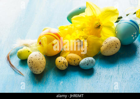 Festive easter frame with yellow daffodils and easter eggs on bright blue wooden background Stock Photo