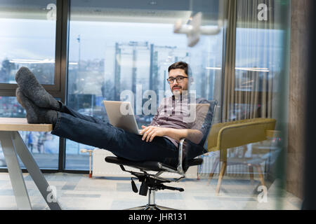 Full length side view of businessman using computer at desk in office Stock Photo