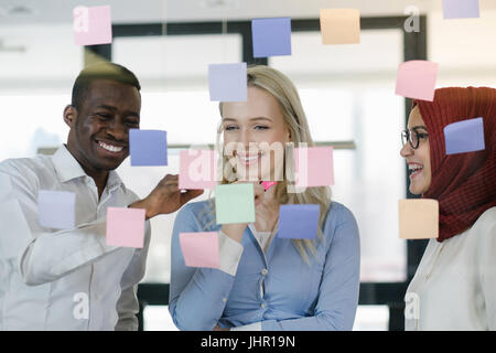 Smiling modern partners looking at sticky notes Stock Photo