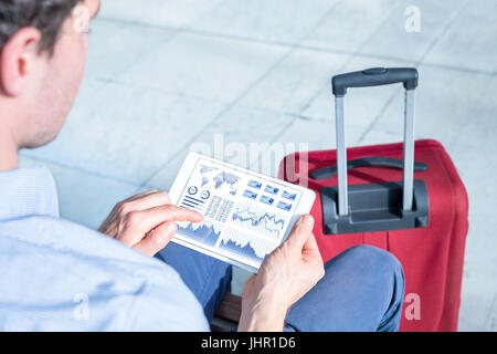 Businessman working with financial dashboard with charts and metrics or electronic banking app on a digital tablet computer at airport Stock Photo