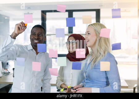 young creative startup business people on meeting at modern office making plans and projects with post stickers on glass Stock Photo