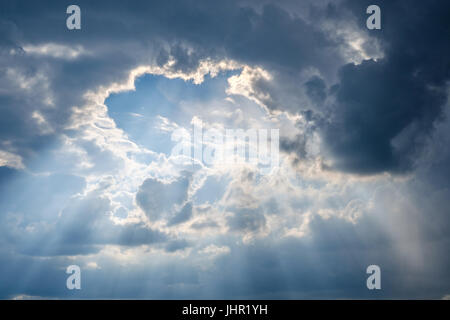 sun rays shining through thick cloudy sky - Stock Photo