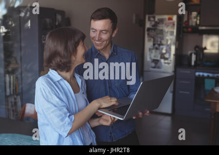 Smiling couple using laptop in living room at home Stock Photo