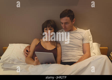 Couple using digital tablet in bedroom at home Stock Photo