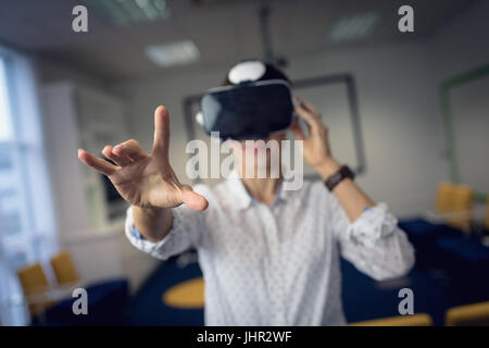 Businesswoman using virtual reality headset in office Stock Photo