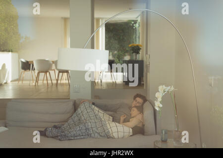 Couple resting on sofa in living room at home Stock Photo