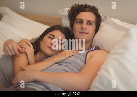 Smiling couple relaxing on bed in bedroom Stock Photo