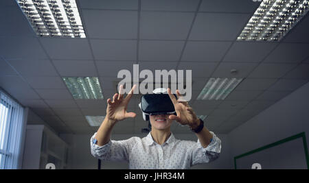 Businesswoman using virtual reality headset in office Stock Photo