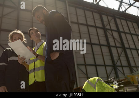 Aircraft maintenance engineers discussing over document at airlines maintenance facility Stock Photo