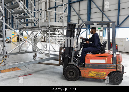 Aircraft maintenance engineer driving forklift truck at airlines maintenance facility Stock Photo