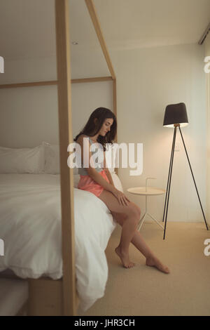 Upset woman sitting on bed at home Stock Photo