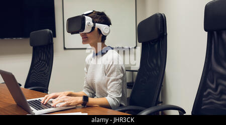 Businesswoman using virtual reality headset in office Stock Photo