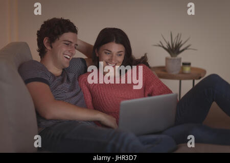 Smiling couple using laptop in living room at home Stock Photo
