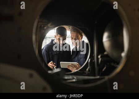 Aircraft maintenance engineers discussing over digital tablet at airlines maintenance facility Stock Photo