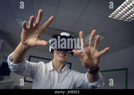 Businesswoman using virtual reality headset in office Stock Photo