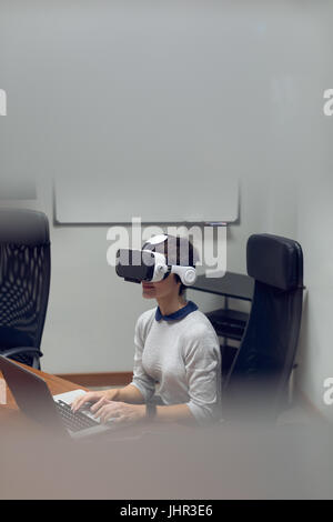 Businesswoman using virtual reality headset in office Stock Photo