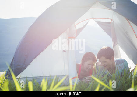 Couple using mobile phone in tent on a sunny day Stock Photo