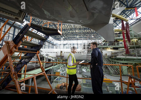 Maintenance engineers discussing over digital tablet at airlines maintenance facility Stock Photo