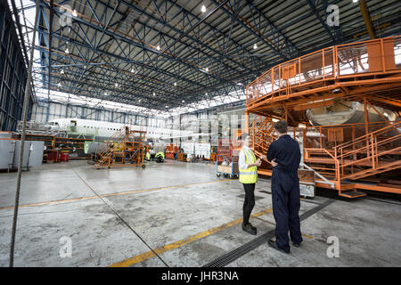 Maintenance engineers interacting with each other at airlines maintenance facility Stock Photo
