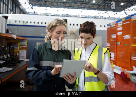 Maintenance engineers discussing over digital tablet at airlines maintenance facility Stock Photo