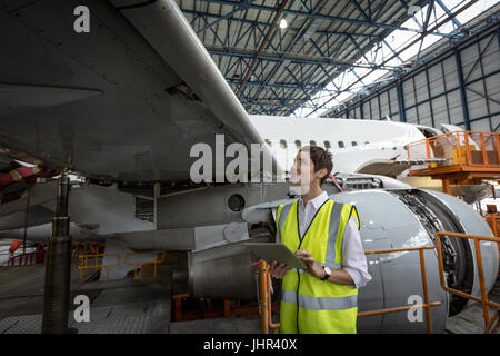 Female aircraft maintenance engineer examining engine of airplane at airlines maintenance facility Stock Photo