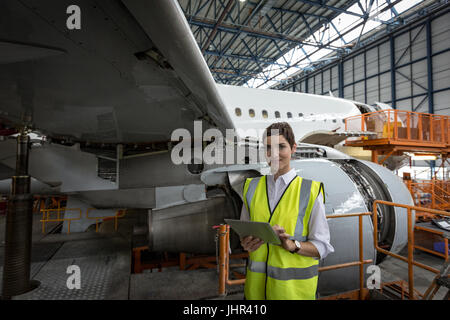 Portrait of female aircraft maintenance engineer using digital tablet at airlines maintenance facility Stock Photo