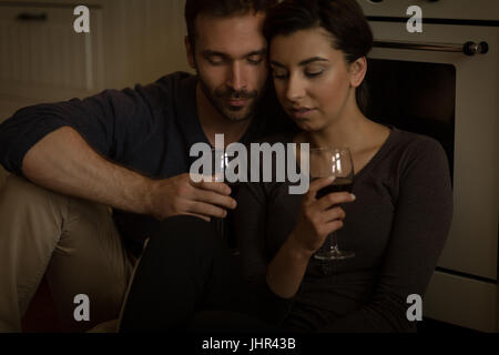 Young couple having wine while sitting in  kitchen at home Stock Photo