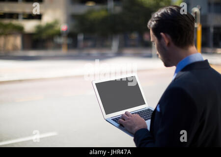 Close-up of businessman using laptop on street Stock Photo