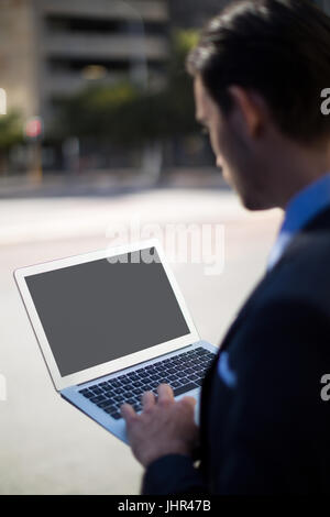 Close-up of businessman using laptop on street Stock Photo
