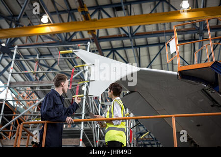 Maintenance engineers interacting with each other at airlines maintenance facility Stock Photo