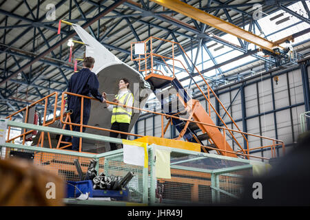 Maintenance engineers interacting with each other at airlines maintenance facility Stock Photo