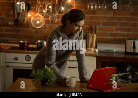 Young woman using laptop in kitchen at home Stock Photo