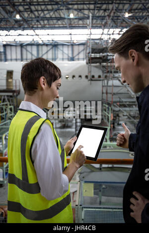 Maintenance engineers discussing over digital tablet at airlines maintenance facility Stock Photo