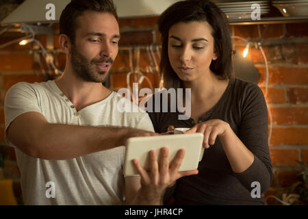 Couple using tablet while standing in kitchen at home Stock Photo