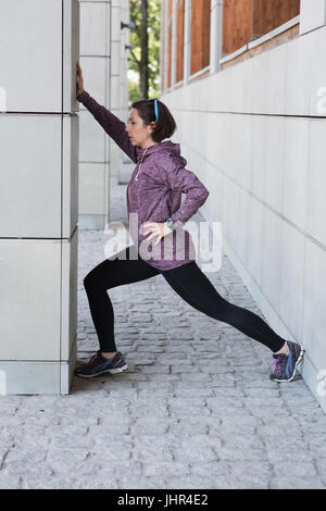 Fit woman performing stretching exercise outside building Stock Photo