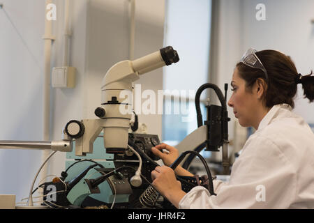 Female technician researcher looking through microscope in laboratory Stock Photo