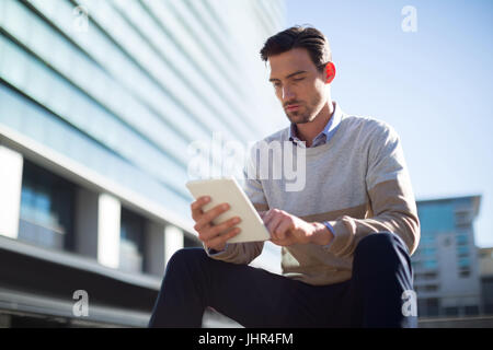 Executive using digital tablet near office building on a sunny day Stock Photo