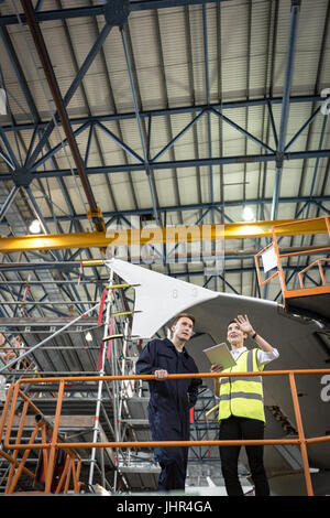 Maintenance engineers interacting with each other at airlines maintenance facility Stock Photo