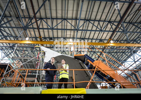 Maintenance engineers interacting with each other at airlines maintenance facility Stock Photo