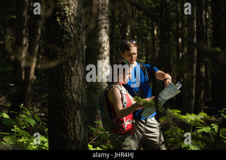 Young couple with map standing in the forest Stock Photo