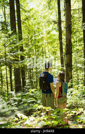 Young couple with map standing in the forest Stock Photo