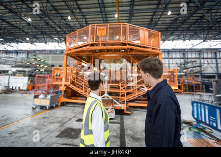 Maintenance engineers interacting with each other at airlines maintenance facility Stock Photo