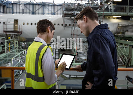 Maintenance engineers discussing over digital tablet at airlines maintenance facility Stock Photo