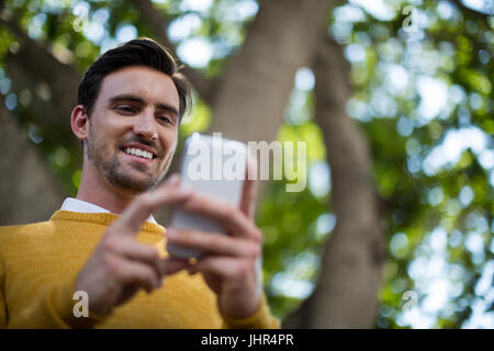 Smiling man using mobile phone in park on a sunny day Stock Photo