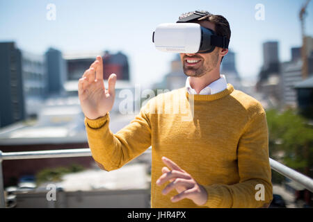 Smiling man using virtual reality headset in balcony Stock Photo