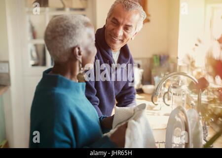 Senior couple talking and doing dishes in kitchen Stock Photo