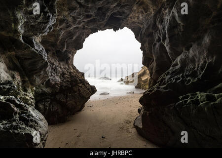 Sandy floor sea cave with motion blur water at Leo Carrillo State Beach in Malibu, California. Stock Photo