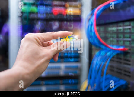 hand with network cables connected to servers in a datacenter Stock Photo