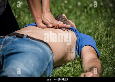 girl making cardiopulmonary resuscitation to an unconscious guy after heart attack Stock Photo
