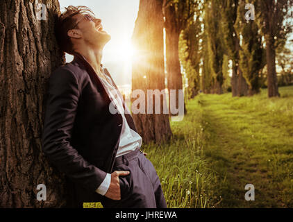 Calm, relaxed guy leaning on the tree Stock Photo